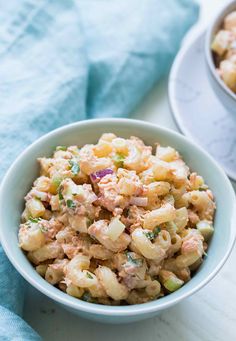 a white bowl filled with macaroni salad on top of a table next to a blue towel