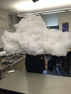 some white clouds are floating in the air over a table and chairs, while people work behind them