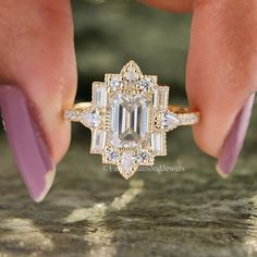 a woman's hand holding a ring with an emerald and white diamond in it