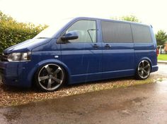 a blue van is parked on the side of the road in front of some bushes