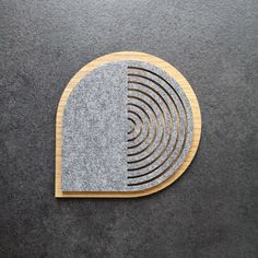 a wooden coaster with grey and white circles on it's side, sitting on a gray carpet