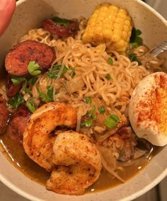 a bowl filled with noodles, shrimp and corn on the cob