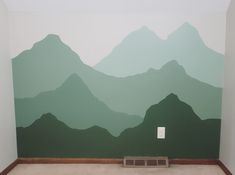 an empty room with mountains painted on the wall and a light switch in the corner