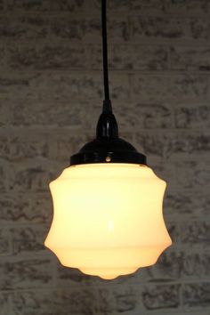 a white light hanging from a ceiling in front of a brick wall