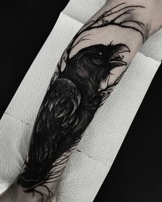 a black and white tattoo on the arm of a person with a crow in it