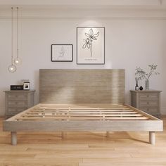 a bed with wooden slats in a white room next to two pictures on the wall