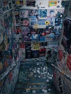 the stairs are covered with posters and stickers in an alleyway that has been vandalized