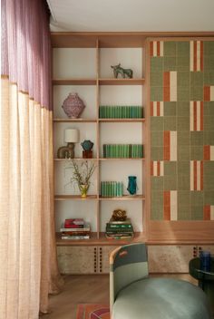 a living room filled with furniture and bookshelves next to a curtained window