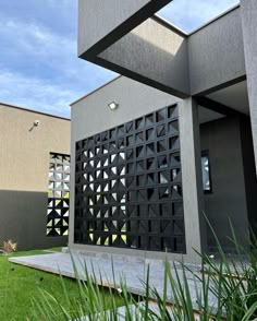 a modern house with an intricate design on the front door and side wall, along with green grass