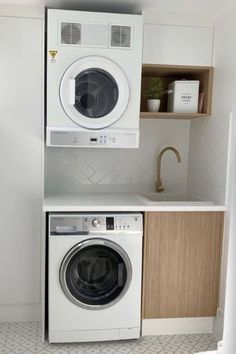 a washer and dryer in a small room with white tile flooring on the walls