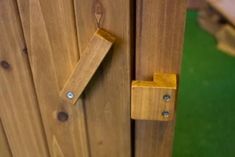 a close up of a wooden door with nails on the wood and green grass in the background