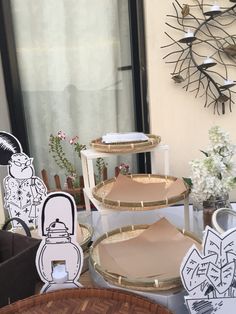 three tiered trays on display in front of a window with paper cutouts