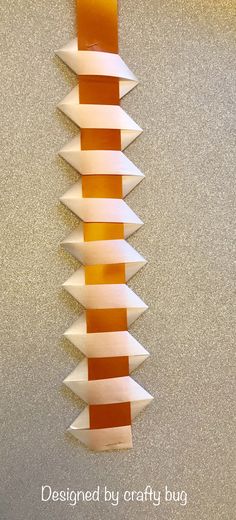 an orange and white sculpture hanging on the wall with words below it that read, designed by crafty bug