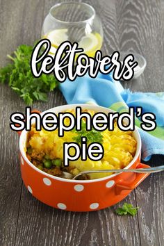 a red bowl filled with shepherd's pie on top of a wooden table