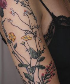 a woman's arm with flowers and leaves on the left side of her body