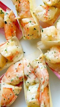 shrimp and scallop salad on a white plate with red utensils in the middle