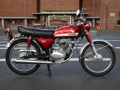 a red and black motorcycle parked in front of a building