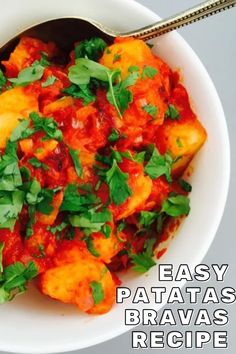 a white bowl filled with food and garnished with parsley next to a spoon