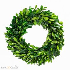 a wreath with green leaves on it is hanging from the wall and ready to be used as an ornament