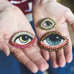 two pairs of handmade beaded rings with an eye on each ring, one being held by someone's hands