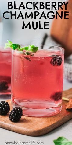 blackberry champagne mules with mint garnish and blackberries on the rim, sitting on a cutting board