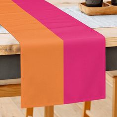 an orange and pink table runner sitting on top of a wooden table