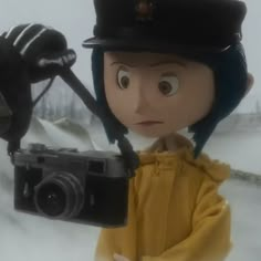 a person holding a camera and wearing a hat in the snow with a spider on it