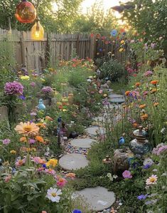 a garden filled with lots of flowers next to a wooden fence and some lights hanging from the ceiling