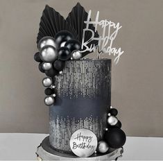 a black and silver birthday cake with balloons on it's side, happy birthday