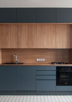 a kitchen with blue cabinets and white tile flooring on the walls, along with an oven and dishwasher