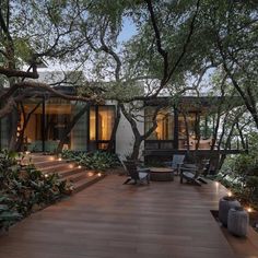 an outdoor deck with chairs and trees in the foreground, surrounded by greenery