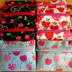 four zippered pouchs with cherries on them sitting on top of a wooden table