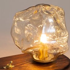 a glass lamp sitting on top of a wooden table next to a small light bulb