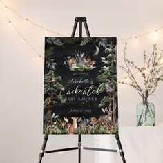 an easel with a wedding sign on it next to a vase and string lights