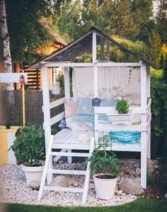 a white gazebo sitting in the middle of a lush green yard with potted plants