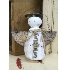 a small white angel figurine sitting on top of a wooden box next to a door