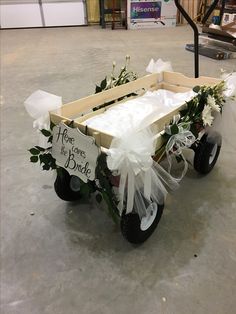 a wagon decorated with flowers and ribbon for a bride's day gift on the floor