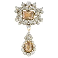 An early Victorian topaz and diamond brooch/pendant, to the centre a cushion-cut orange topaz measuring approximately 8.2 x 6.2mm, cut-down set in yellow gold collet with closed back, surrounded by a diamond-set scroll design frame, suspending a pear-shaped drop, centrally-set with a pear-shaped topaz measuring approximately 8.2 x 5.7mm, surrounded by old mine cut diamonds, the old-cut diamonds estimated to weigh 4 carats in total, all mounted in silver and gold, with gold brooch fitting and fol Victorian Pendant Necklace, Antique Jewelry Victorian, Diamond Centerpiece, Victorian Pendants, Design Frame, Gold Brooch, Antique Pendant, Cultured Pearl Necklace, Antique Brooches