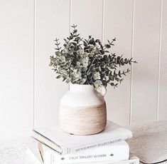 three books stacked on top of each other next to a vase with flowers in it