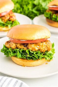 chicken burgers with lettuce and tomato on white plates