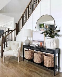 a living room filled with furniture and a mirror on top of a wooden table next to a stair case