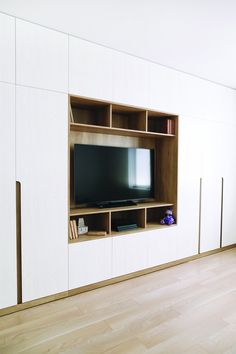 an entertainment center with a television and bookshelf in the corner, on top of a hard wood floor