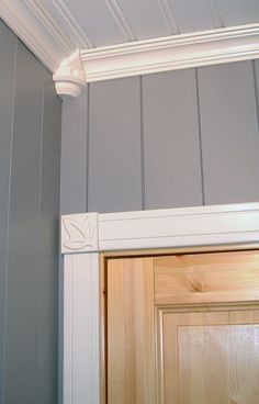 the corner of a room with a wooden door and white molding on the wall