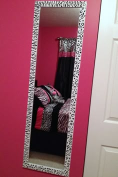 a mirror that is on the wall in front of a pink wall with black and white decor