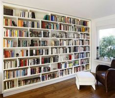 a large book shelf filled with lots of books in a living room next to a window