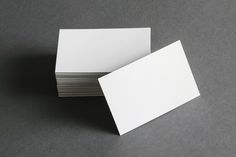 several white business cards stacked on top of each other in front of a gray background