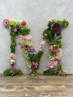 the letter m is made out of moss and flowers