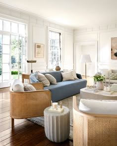 a living room filled with lots of furniture next to two large windows on the wall