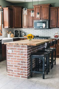 a kitchen with an island made out of bricks and stools next to the counter