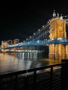 the bridge is lit up at night and it looks like it's going over water